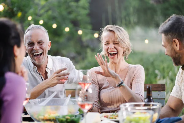 Couple having fun time at dinner with friends, laughing and drinking wine
