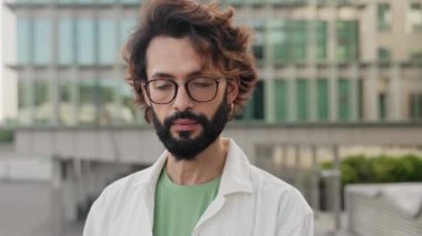 Sakallı ve gözlüklü mutlu genç adam kameraya gülümsüyor. 