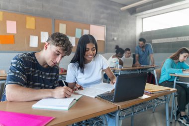 Teenager classmates doing exercise and working together in the Secondary School Classroom - Multi ethnic caucasian and Latin American students