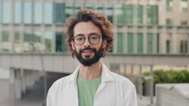 Young hispanic man with beard and eyeglasses looks to the camera with happy expression. Human emotion and feelings