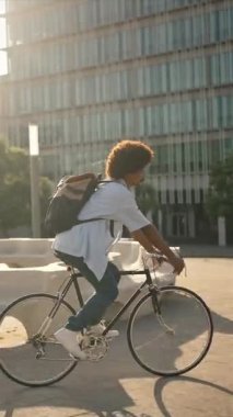 Young African American man riding bike in the city - vertical video