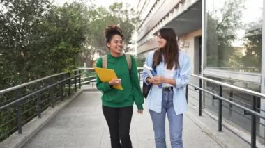 Female student friends having conversation going out University building