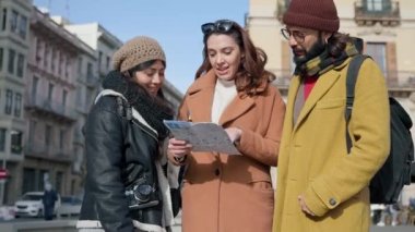 Friends checking city map searching for tourist destination in winter vacations 