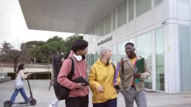 Happy university female student and her African American and Asian friends walking and talking after the lecture at college campus