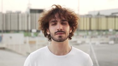 Young caucasian man with beard and curly hair smiling looking to camera confident and happy