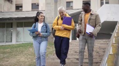 University students wearing casual clothes carrying backpacks and notebooks walking on campus talking. Diversity in Higher education 