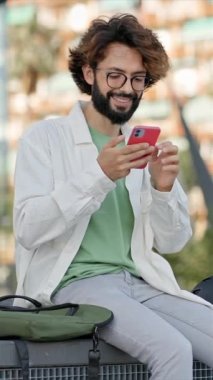 Young happy man using cell phone app in the city - Positive person reading good news vertical video