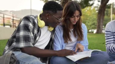 African man university student working and learning together with female friend sitting on campus grass