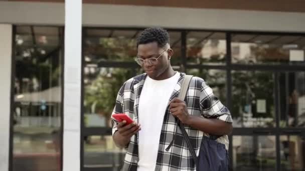 Happy African Student Walking Out University Building Using Cell Phone — Video