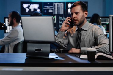 Başarılı tüccar iş adamı, yoğun modern ofislerdeki bilgisayar ekranlarını kullanarak borsaya yatırım yapıyor.