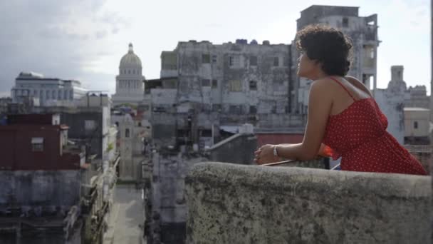 在古巴的家中阳台上凝视着哈瓦那市的年轻拉丁美洲妇女 — 图库视频影像