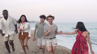 Çoklu etnik gruptan mutlu arkadaşlar yazın plajda koşuşturuyor. 