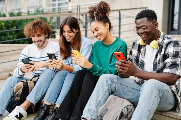 Yliopiston Opiskelijat Istuvat Portaikossa Kirjoittamalla Älypuhelimilla Monikulttuurinen Ryhmä Ystäviä Matkapuhelimilla — kuvapankkivalokuva
