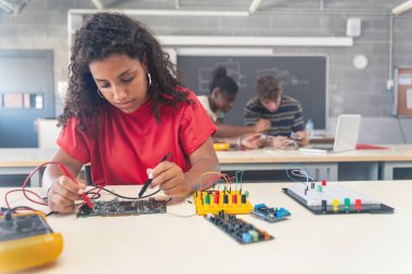 Teknoloji dersinde elektronik robotik üzerinde çalışan Afrikalı Amerikalı kız öğrenci.