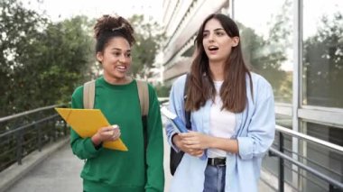 Üniversite öğrencisi iki kız arkadaş üniversite kampüsünde konuşuyor ve dolaşıyorlar.