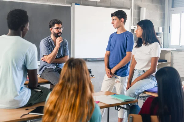 Gruppe Tenåringer Mannslærer Klasserommet Som Snakker Diskuterer Sammen stockfoto