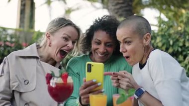 Sosyal medyanın içeriğini paylaşmak için cep telefonu kullanan bir grup kadın arkadaş - sürpriz ve iyi haber
