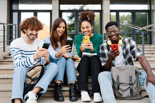 Усміхнені Студенти Університету Друзі Використовують Мобільні Пристрої Разом Переглядаючи Смішне — стокове фото