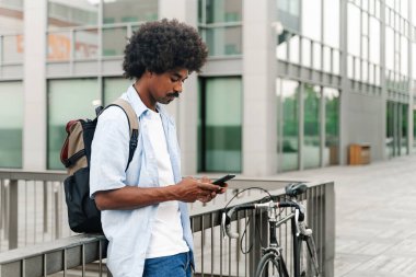 Şehirde cep telefonu kullanan bisikletli genç Afrikalı Amerikalı adam.