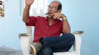 Yaşlı İspanyol adam verandada dinleniyor geleneksel Küba purosu içerken komşularını selamlamıyor.