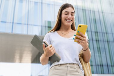 Modern şehrin iş yeri bölgesinde cep telefonu kullanan kendine güvenen genç sarışın kadın - Öğrenci stajyerliği 