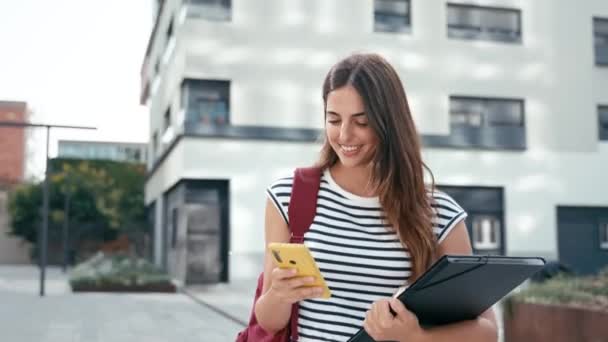 Νεαρή Ισπανίδα Γυναίκα Περπατάει Ενώ Χρησιμοποιεί Κινητό Της Χαρούμενη Φοιτήτρια — Αρχείο Βίντεο