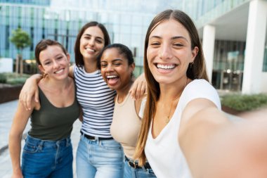Şehirde fotoğraf çeken mutlu arkadaşlar - Uluslararası öğrenci kızlar sosyal medyada akademik dersi kutluyorlar