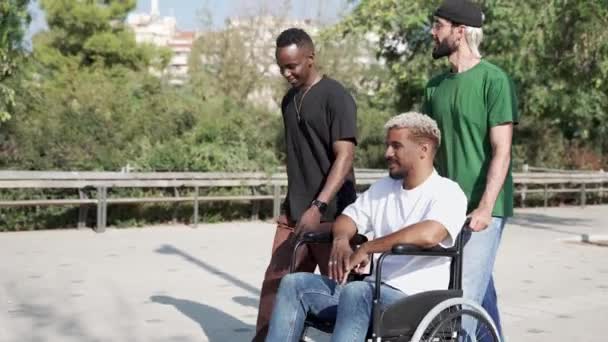 Молоді Багатоетнічні Друзі Штовхають Інвалідний Візок Інваліда Під Час Розмови — стокове відео