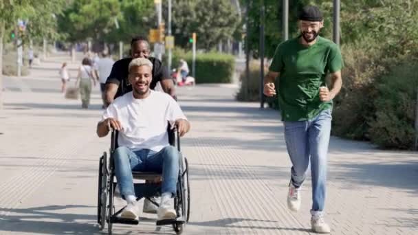 Młodzi Przyjaciele Biegający Niepełnosprawnym Wózku Inwalidzkim Czują Wolność Zabawy Parku — Wideo stockowe
