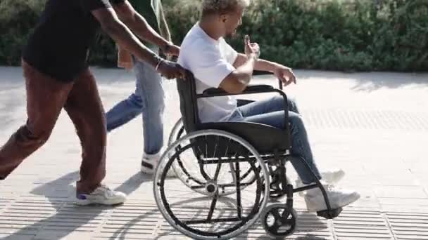 Молодые Друзья Толкают Инвалидную Коляску Веселятся Вместе Гуляя Городском Парке — стоковое видео