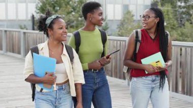 Bir grup Afrikalı Amerikalı üniversiteli kız arkadaş kampüsten konuşuyor ve çıkıyorlar. 