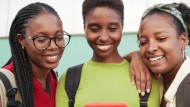 Afrikalı Amerikalı üniversite öğrencisi kız arkadaşları sosyal medyada içeriği paylaşmak için cep telefonu kullanıyorlar