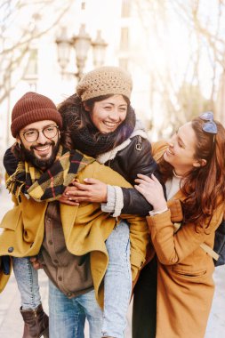 Arkadaş grubumuz birlikte gülüyor. Asyalı kadın ve İspanyol adam kışın eğleniyor. 
