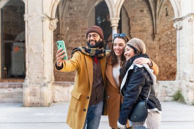 Arkadaşlar kışın birlikte fotoğraf çektirip turistik yerleri geziyorlar.
