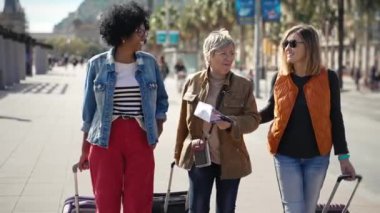 Üç kadın turist arkadaş şehir caddesinde yürüyor, hafta sonu tatilinin tadını çıkarıyorlar.
