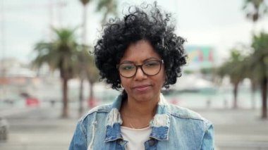 Şehirde gözlüklü ve kot ceketli gülümseyen Latin Afrikalı Amerikalı kadının portresi 