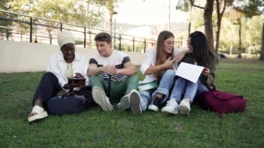 Üniversite ögrencisi arkadaslari çimde oturuyor, kolej kampüsünde birlikte çalisiyorlar. Afrikalı Amerikan gençliği