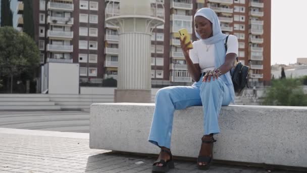 Młoda Muzułmanka Niebieskim Hidżabem Pomocą Żółtej Aplikacji Komórkowej Mieście — Wideo stockowe