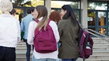 Üniversite öğrencisi kız arkadaşları üniversiteye geliyor, okul binasına girmek için yürüyen merdivenler. 