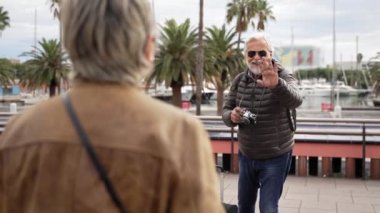 Yaşlı bir adam, yaşlı bir çiftin emekliliğinin tadını çıkardığı turistik bir gezi sırasında karısının fotoğrafını çekiyor.