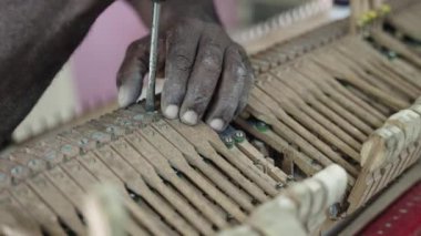 Yaşlı adam Luthier müzik ustası ahşap büyük piyano klavyesini tamir ediyor ve akort ediyor.
