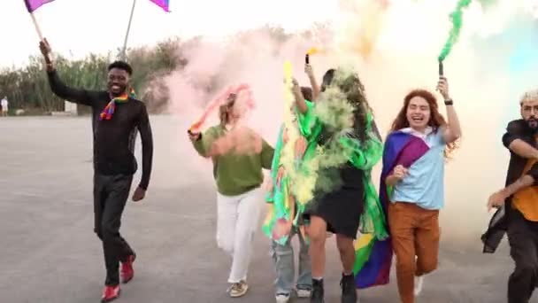 カラフルな煙でゲイプライドフェスティバルを楽しんで レインボーフラッグを開催する通りで踊る人々のグループ — ストック動画
