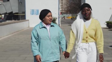 Genç Müslüman kız arkadaşlar şehirde birlikte yürüyorlar, sevgi ve sevgiyle - kadın arkadaşlığı