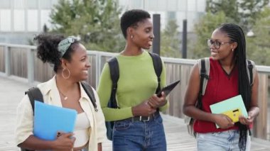Afrikalı Amerikalı öğrenci arkadaşlar üniversite kampüsünde iyi vakit geçirmekten bahsediyorlar. 