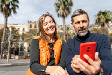 Sosyal medyadaki içeriği paylaşmak için cep telefonu kullanan birkaç arkadaş birlikte oturuyor - sürpriz ve iyi haber