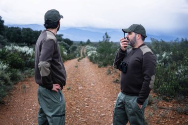 Team of Park Rangers with uniform using Walkie Talkie radio to monitor wildlife in the nature reserve clipart