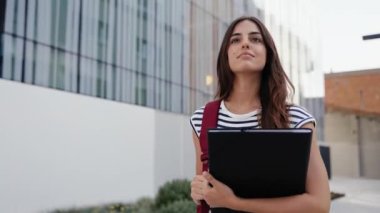 Ekonomi ve İşletme Fakültesi binasının önünde yürüyen ilham verici bir kadın öğrenci.