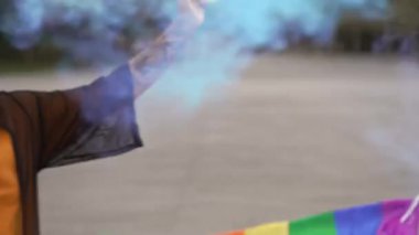Genç adam renkli dumanlı bir gay festivalinde arkadaşlarıyla dans ediyor. 