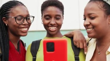 Sosyal medyada içeriği paylaşmak için cep telefonu kullanan Afrikalı Amerikalı öğrenci kızlar - cep telefonuyla eğlenen arkadaşlar