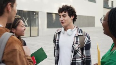 Genç İspanyol öğrenci ve bir grup arkadaşı üniversite binasının önünde toplanıp okul projesi hakkında konuşuyorlar. 